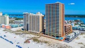 Un hôtel en bord de mer, composé de plusieurs immeubles de grande hauteur, avec une plage équipée de transats et offrant une vue dégagée sur l’océan.