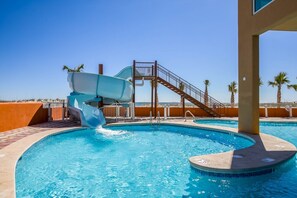 A swimming pool with a water slide, a staircase, and palm trees in the background. - Phoenix Gulf Shores by Brett/Robinson Vacations (Gulf Shores)