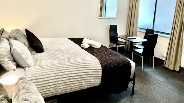 A hotel room with a bed, a desk, a chair, and a window with curtains. - LOVELY ADELAIDE CITY ESCAPE (Adelaide)
