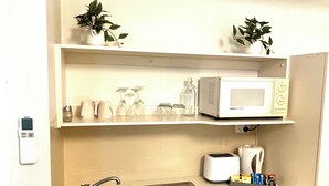 A compact kitchenette with a microwave, toaster, sink, and small potted plants. - LOVELY ADELAIDE CITY ESCAPE (Adelaide)