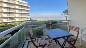 Ein Balkon mit Tisch und Stühlen, mit Blick auf die Küste und Gebäude im Hintergrund.