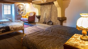 A rustic room with a bed, a chair, a bookshelf, and a stone wall with pots. - Charming medieval house in the heart of Hérisson (Hérisson)