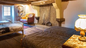 Una habitación rústica con una cama grande, una silla, una estantería y una pared de piedra con macetas.