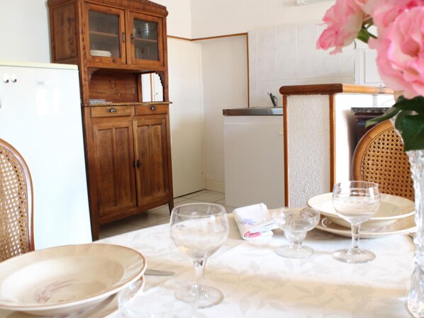 A dining area with a table set for four, a wooden cabinet, and a white refrigerator.