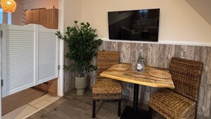 Un espace repas comprenant une table, des chaises, une plante en pot et un téléviseur fixé au mur.