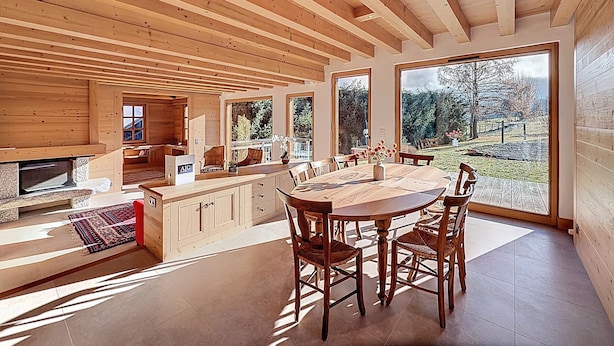 A spacious wooden interior with a large dining table, chairs, and a kitchen area. - Spacious 5-bedroom chalet near ski bus, Mont Blanc view (Combloux)