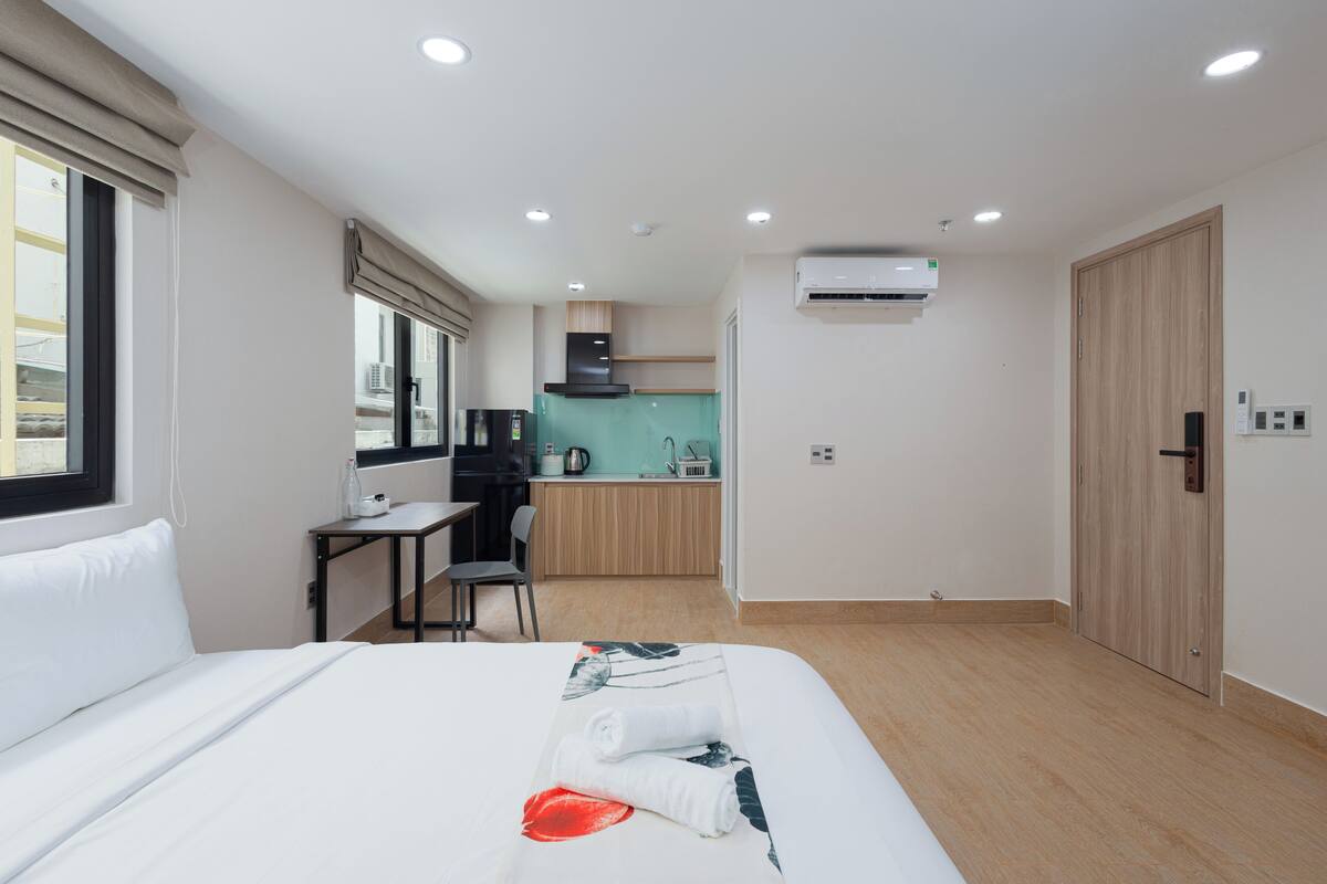 Ein Hotelzimmer mit Bett, Schreibtisch, Stuhl, einer Küchenzeile und einer Klimaanlage.