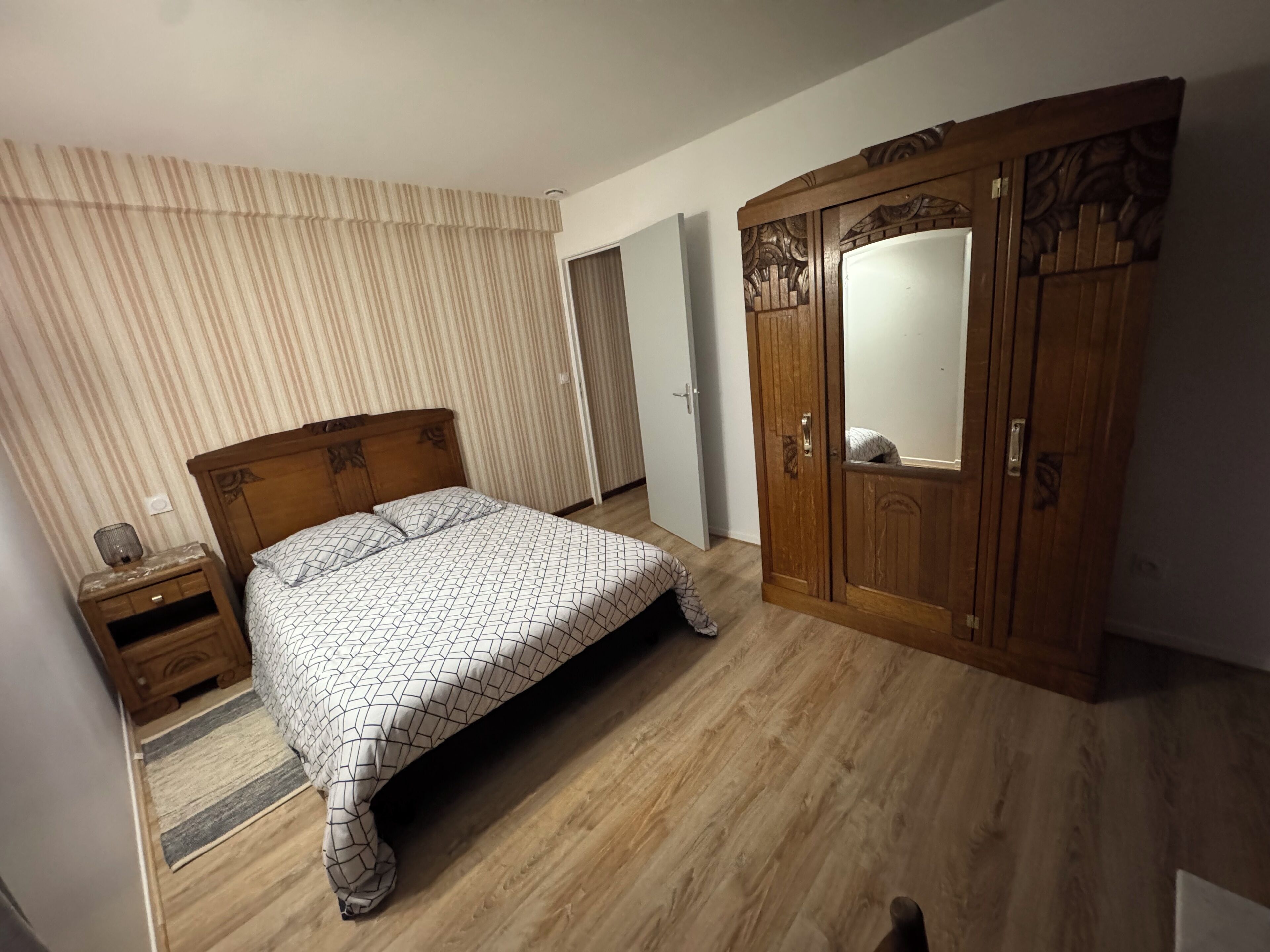 Un dormitorio con una cama de madera, un armario y un espejo.
