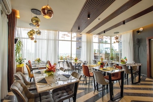 A spacious dining area with multiple tables and chairs, large windows, and hanging spherical light fixtures.