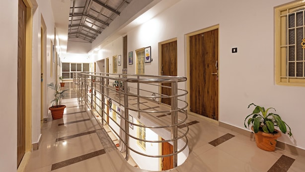 A corridor with a metal railing, potted plants, and wooden doors. - Treebo Golden Paradise (Yercaud)