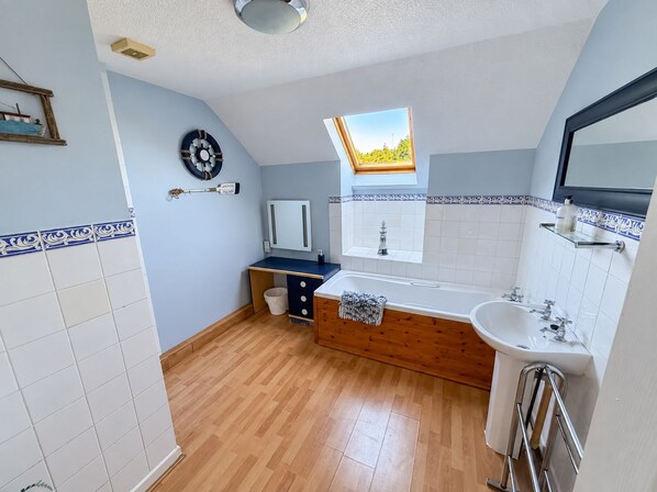 Ein modernes Badezimmer mit einem Holzkosmetikschrank, einer freistehenden Badewanne und einem Oberlicht.