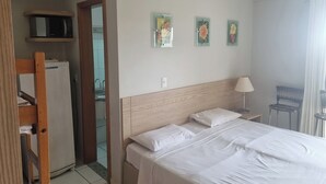 A hotel room with a bed, a desk, a chair, a microwave, and a refrigerator. - Modern apartment with complete leisure area and access to the Golden Dolphin. (Caldas Novas)