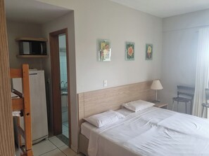 A hotel room with a bed, a desk, a chair, a microwave, and a refrigerator. - Modern apartment with complete leisure area and access to the Golden Dolphin. (Caldas Novas)