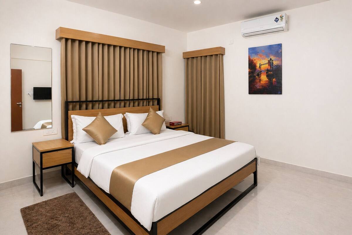 A modern hotel room with a large bed, a nightstand, a mirror, an air conditioning unit, and a painting on the wall.
