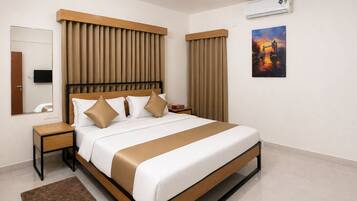 A modern hotel room with a large bed, a nightstand, a mirror, an air conditioning unit, and a painting on the wall.