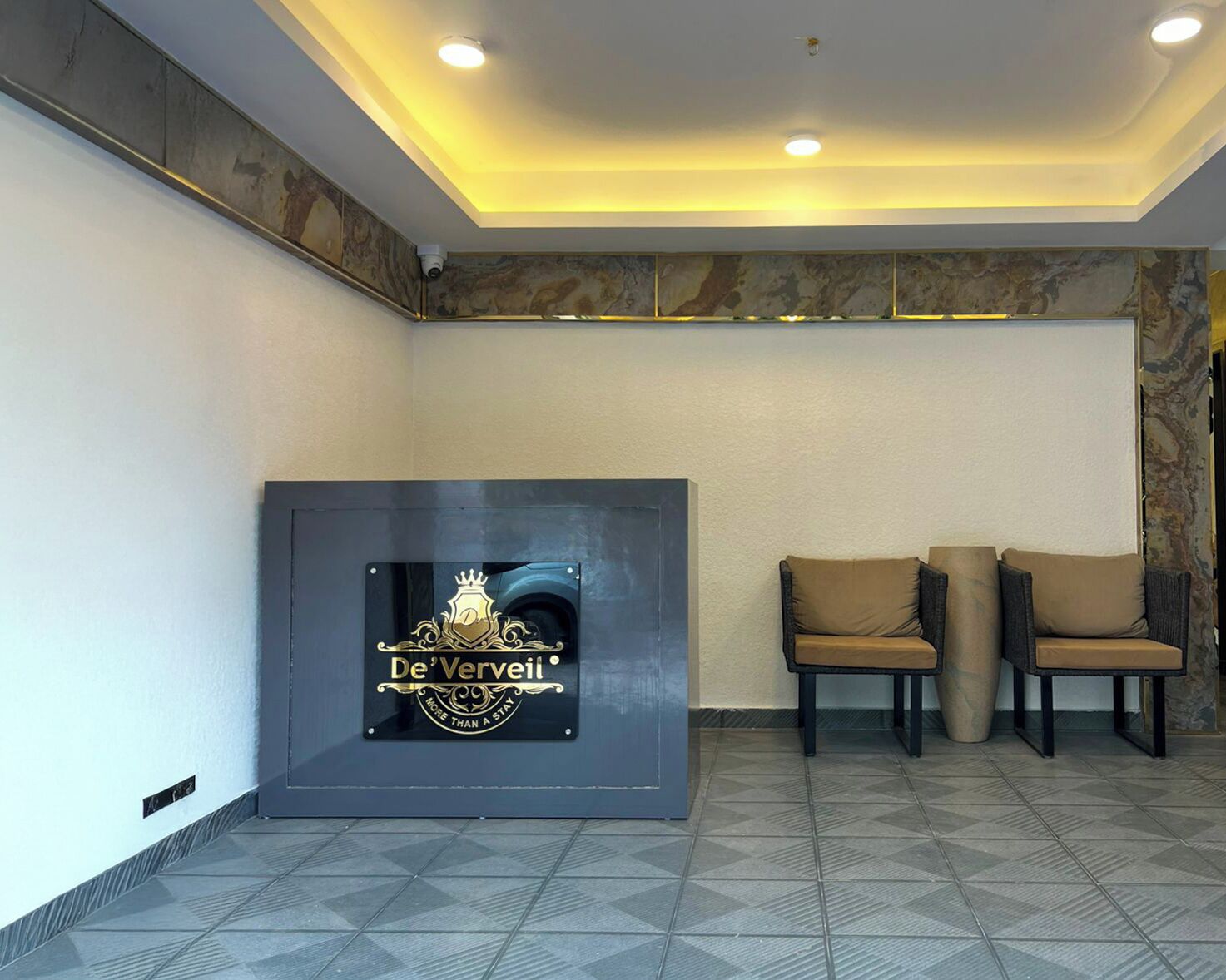 Un espace d’accueil avec un logo sur le mur, deux chaises et un sol à motifs.