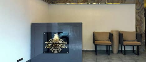 Un espace d’accueil avec un logo sur le mur, deux chaises et un sol à motifs.