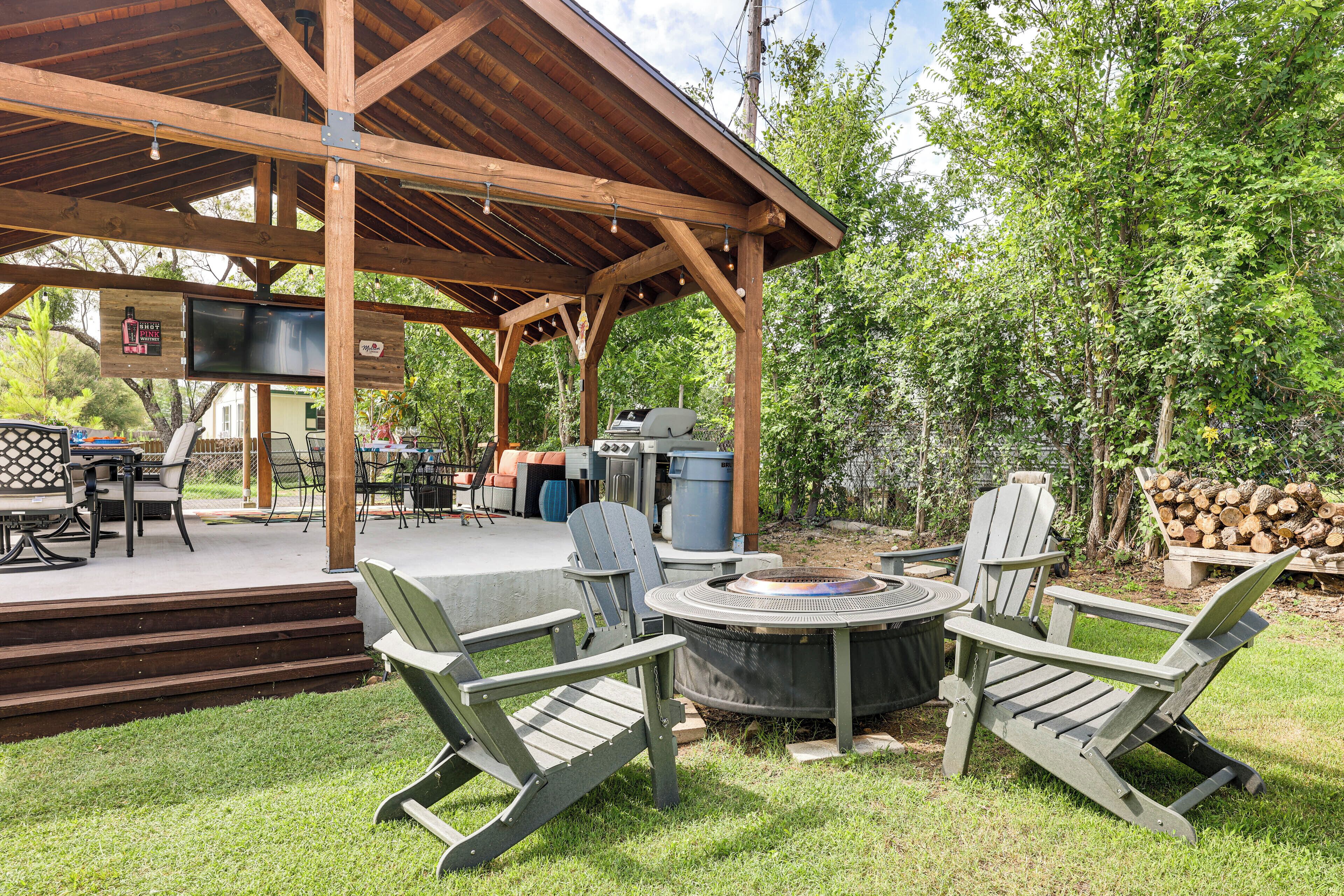 Une terrasse extérieure équipée d’un barbecue, de fauteuils Adirondack et d’un foyer.