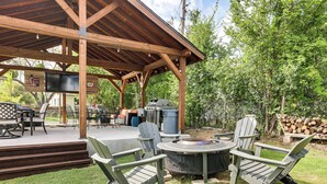 An outdoor patio with a grill, Adirondack chairs, and a fire pit. - Lake LBJ Home: Putting Green, Pavilion & Fire Pit (Kingsland)