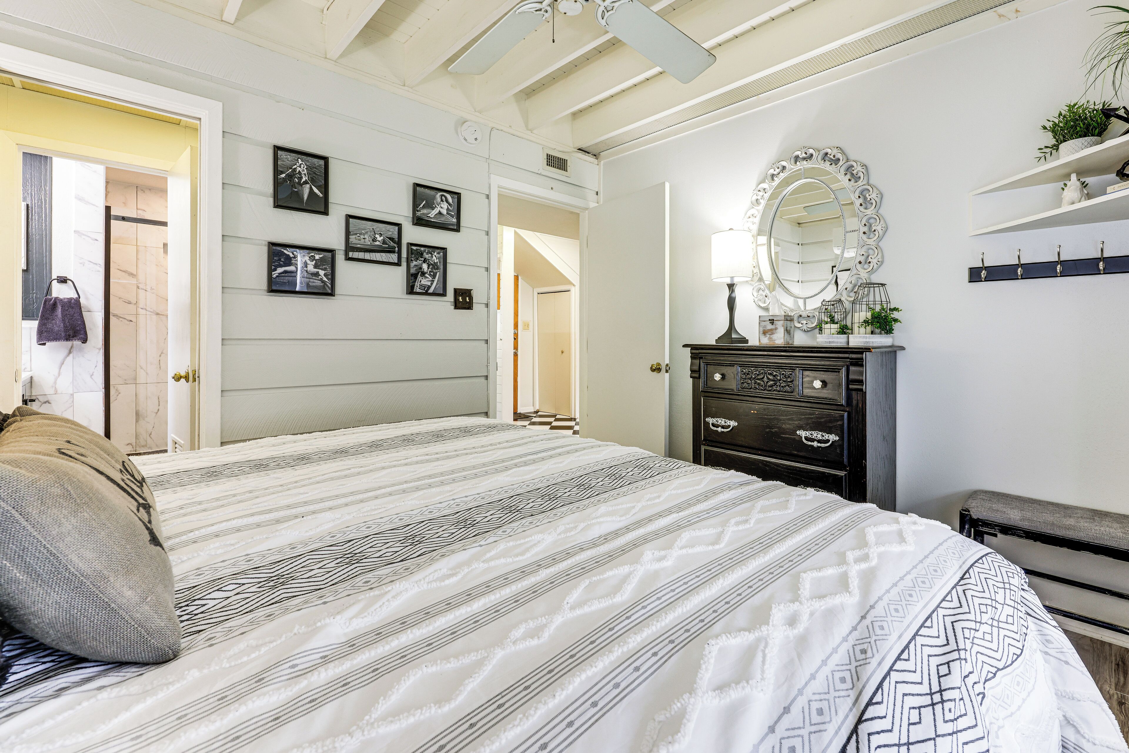 A bedroom with a large bed, a dresser, a mirror, and wall-mounted shelves.