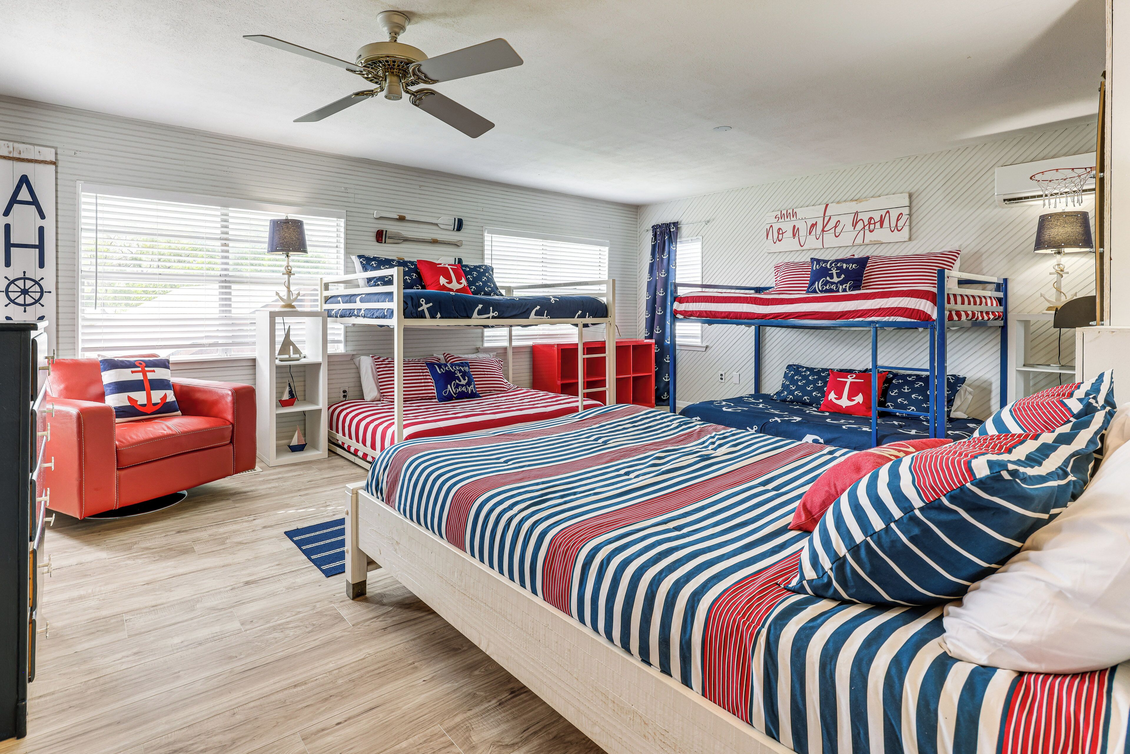 A room with bunk beds, a red sofa, and a ceiling fan.