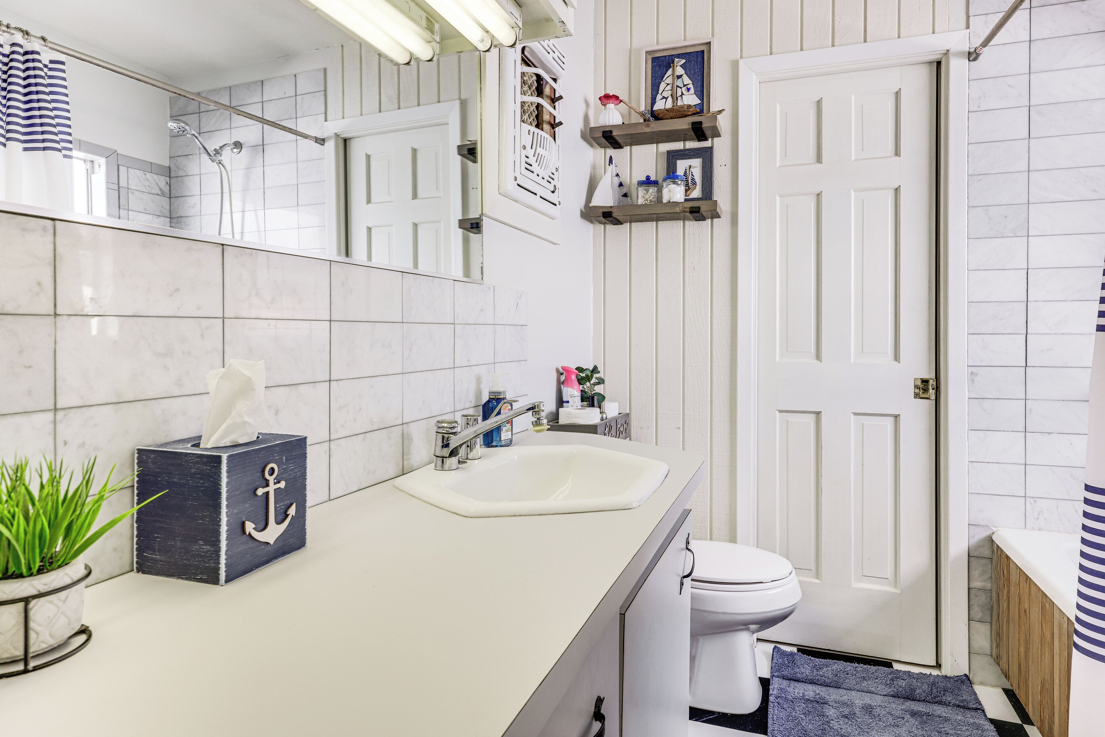 A bathroom with a white sink, a toilet, a towel rack, a mirror, and a potted plant.