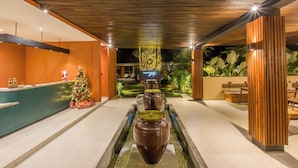 A modern lobby with a central water feature, wooden paneling, and a Christmas tree.