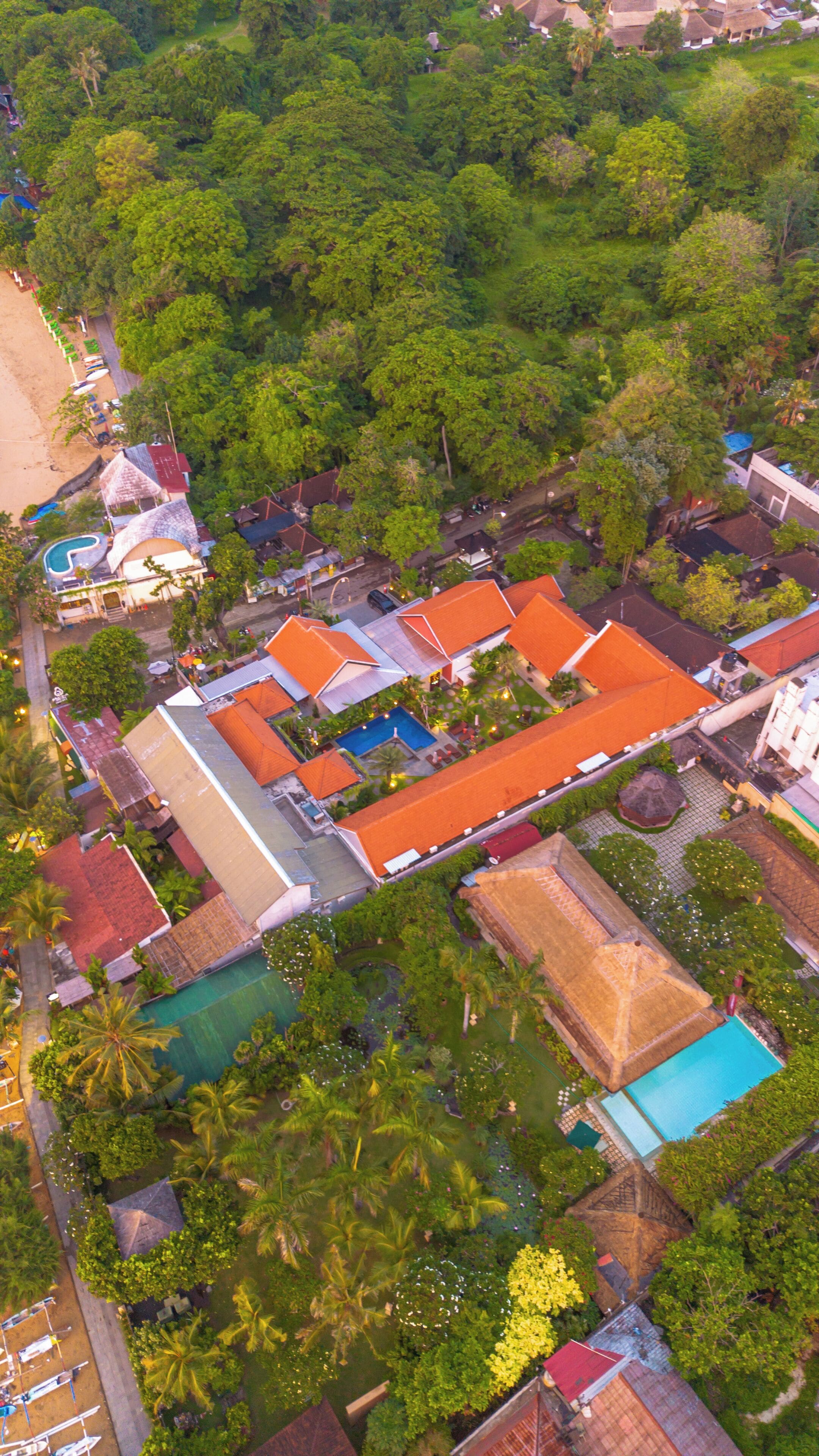 An aerial view of a resort with multiple buildings, a swimming pool, and lush greenery.