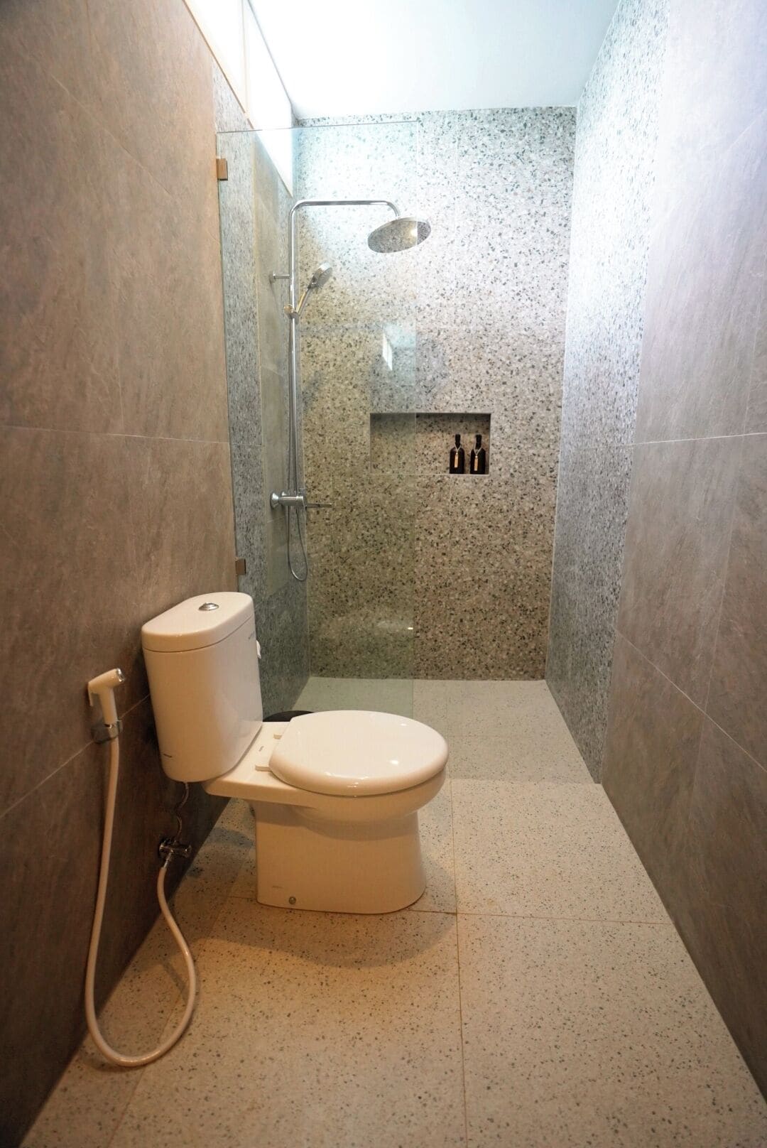 A bathroom with a toilet, a shower, and a glass-enclosed shower area.