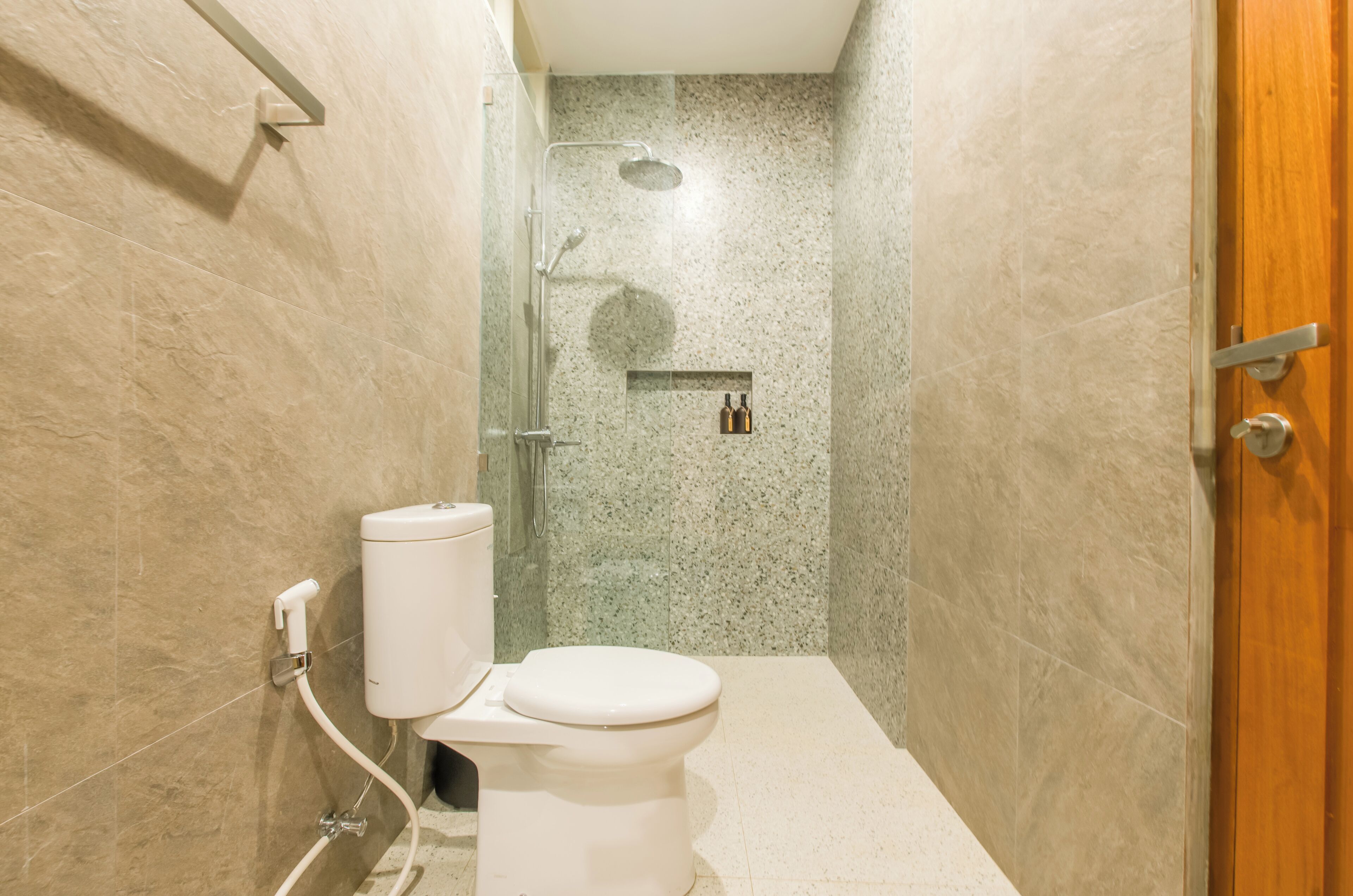 Une salle de bain avec des toilettes, une douche et une porte en bois.