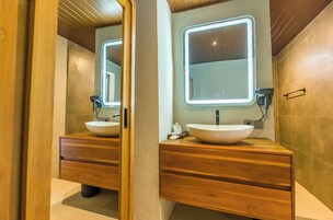 Un baño con dos tocadores de madera, cada uno con un espejo grande y un lavabo redondo.