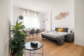 Ein modernes Hotelzimmer mit Bett, Schreibtisch, Essbereich und einer großen Zimmerpflanze.