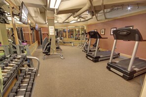 Ein Fitnessstudio mit Laufbändern, Hanteln und Trainingsgeräten.