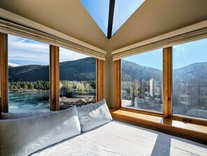A bedroom with a large bed, wooden window frames, and a view of a river and mountains. - Lake Views, Sleeps 6, New Listing! (Keystone)