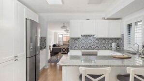 Eine moderne Küche mit weißen Schränken, einer Granitarbeitsplatte und einer gemusterten Spritzschutzwand.