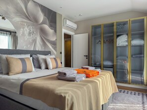 Une chambre d’hôtel moderne dotée d’un grand lit, d’un dressing avec des portes en verre et d’une fresque murale décorative.