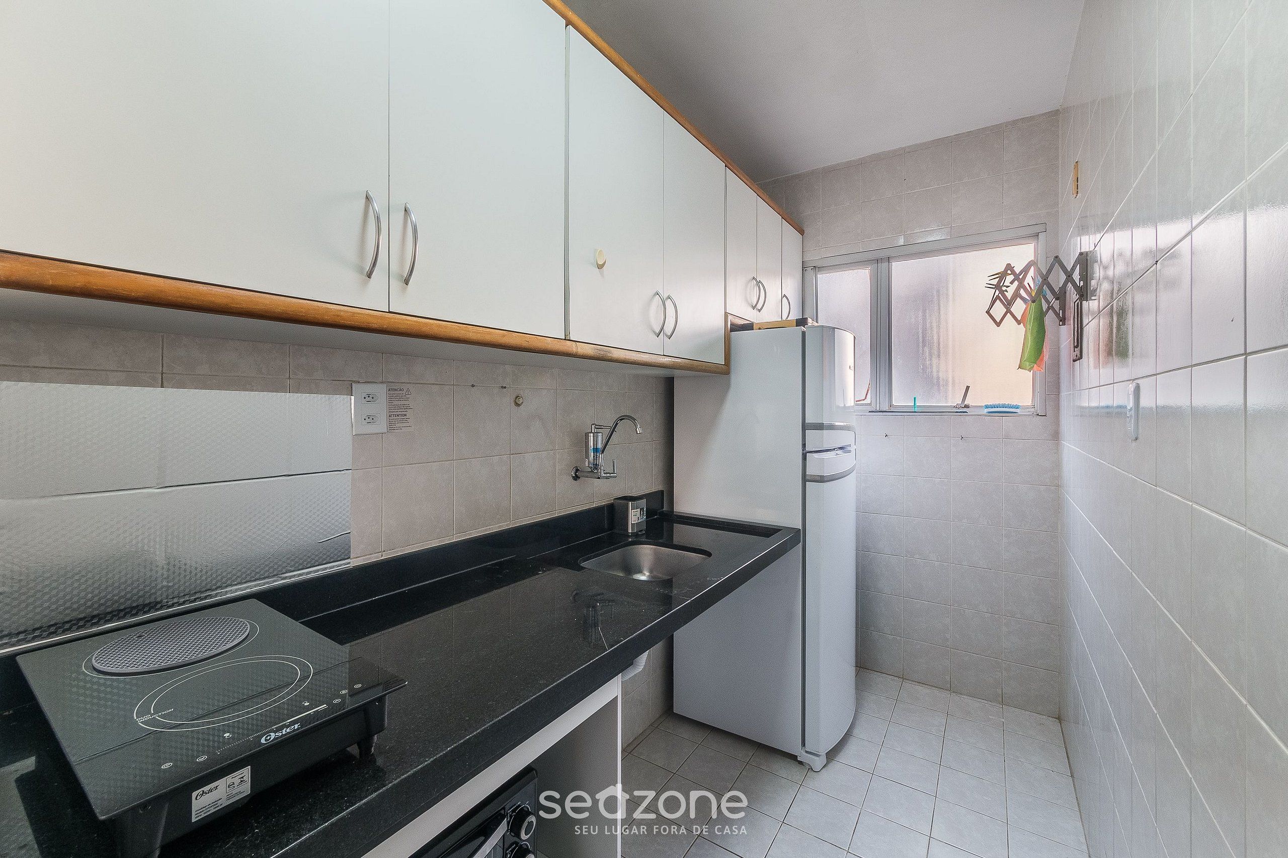 A kitchen with white cabinets, a black countertop, a built-in stove, and a refrigerator.