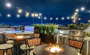 An outdoor patio with round tables, chairs, a fire pit, and a grill. - Lux Nash Party•10 Beds•Hot Tub•Game Room + Pool (Nashville)