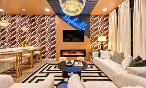Un salon moderne avec une cheminée, un coin repas avec une longue table et un ensemble de canapés.