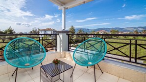 A balcony with two turquoise chairs, a small table, and a potted plant. - Irene Luxury Villa in Zakynthos (Zakynthos)