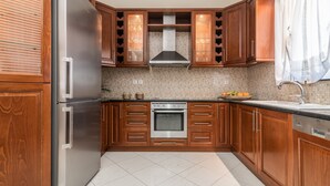 A kitchen with wooden cabinets, a stainless steel refrigerator, a built-in oven, and a tiled backsplash. - Irene Luxury Villa in Zakynthos (Zakynthos)