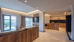Uma sala de estar moderna com um banco de madeira, área de cozinha com bancada de madeira e uma janela grande que oferece vista para o exterior.