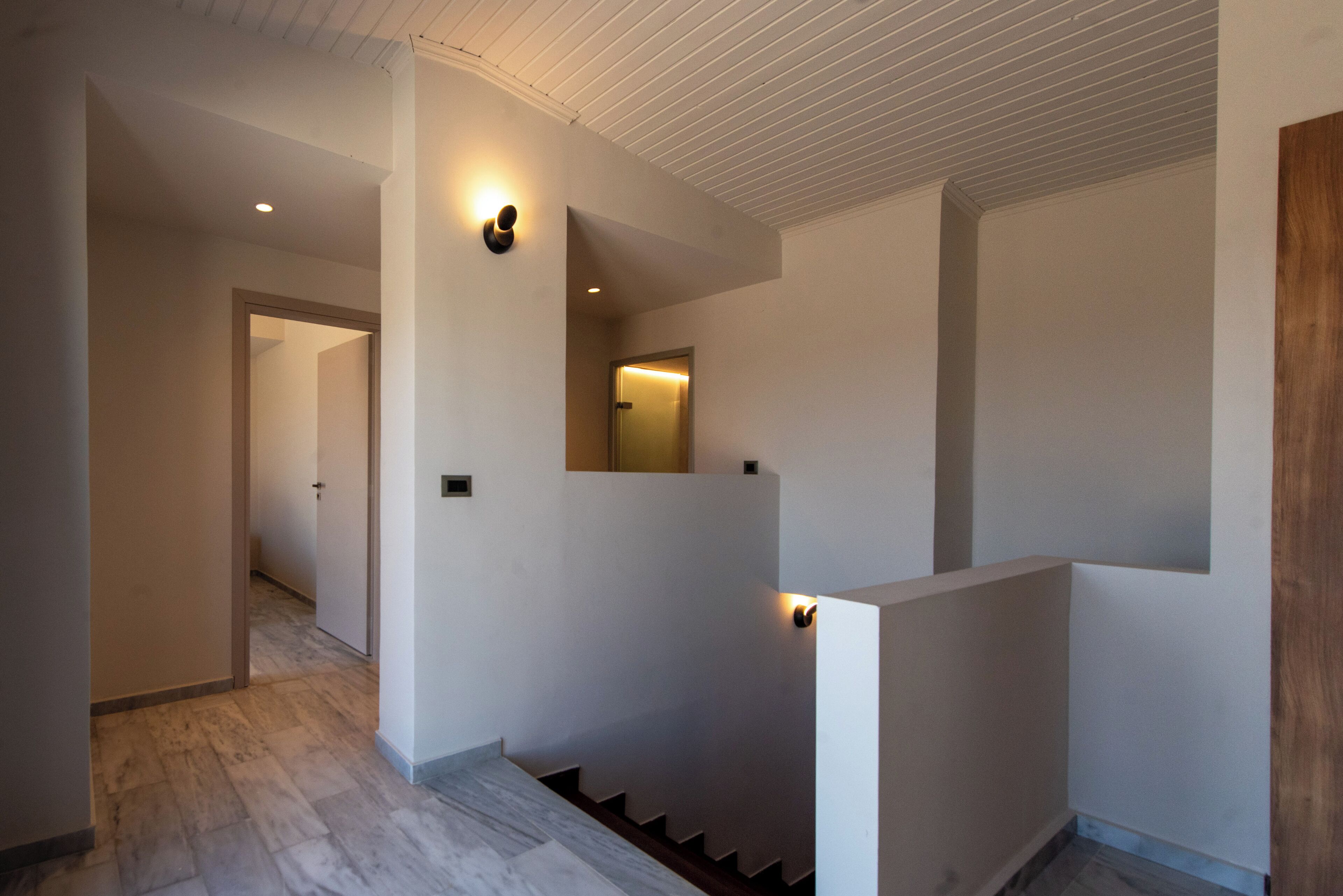 Ein modernes Interieur mit Treppe, weißen Wänden und eingelassener Beleuchtung.