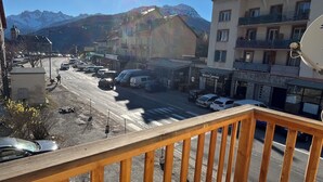 Un balcón con vista a una calle, edificios y montañas.