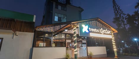 A building with a sign that reads "treebo Ezealude" at night.