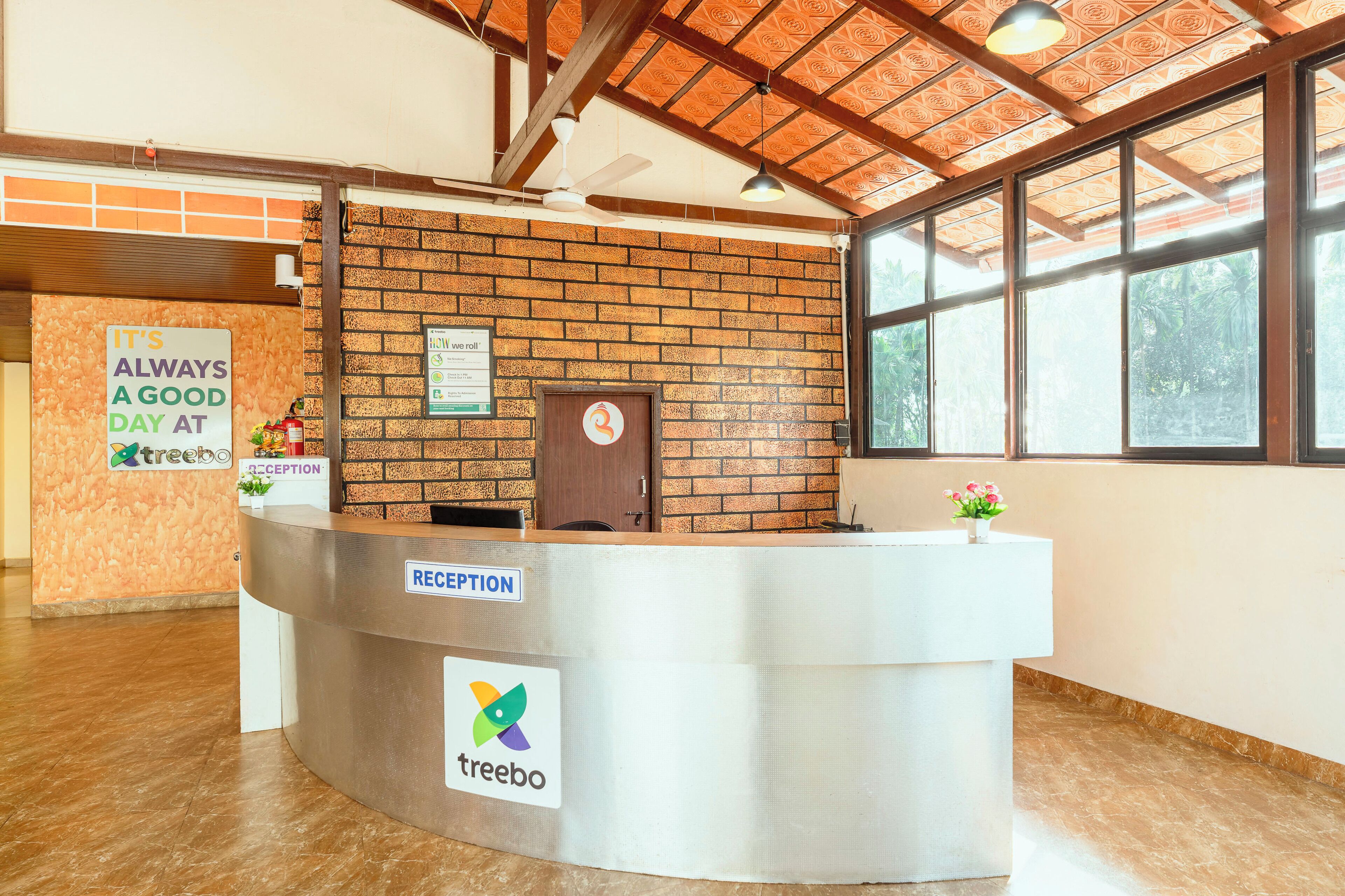 A reception desk with a brick wall backdrop, a ceiling fan, and a window providing natural light.