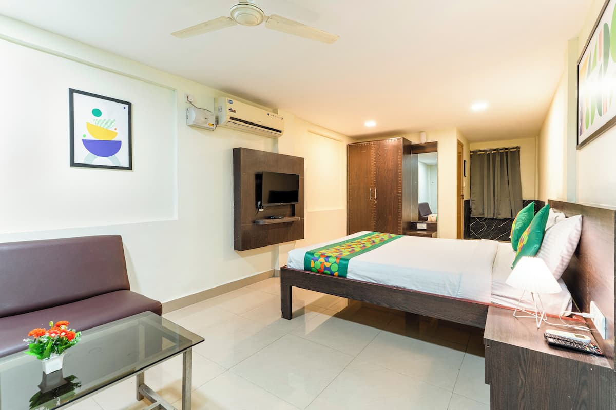 Una habitación de hotel con cama, sofá, televisor y ventilador de techo.