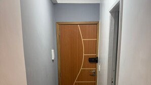 A narrow hallway with a wooden door featuring a geometric design, a light switch, and a door handle. - Studio Paris - Downtown Niterói (Niterói)