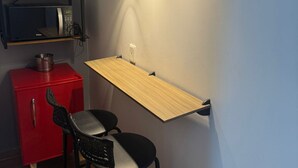 A compact kitchenette with a microwave, a red cabinet, and a wooden shelf. - Studio Paris - Downtown Niterói (Niterói)