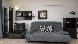 Una sala de estar moderna con un sofá gris, un televisor de pantalla plana, una mesa de centro y un mueble.